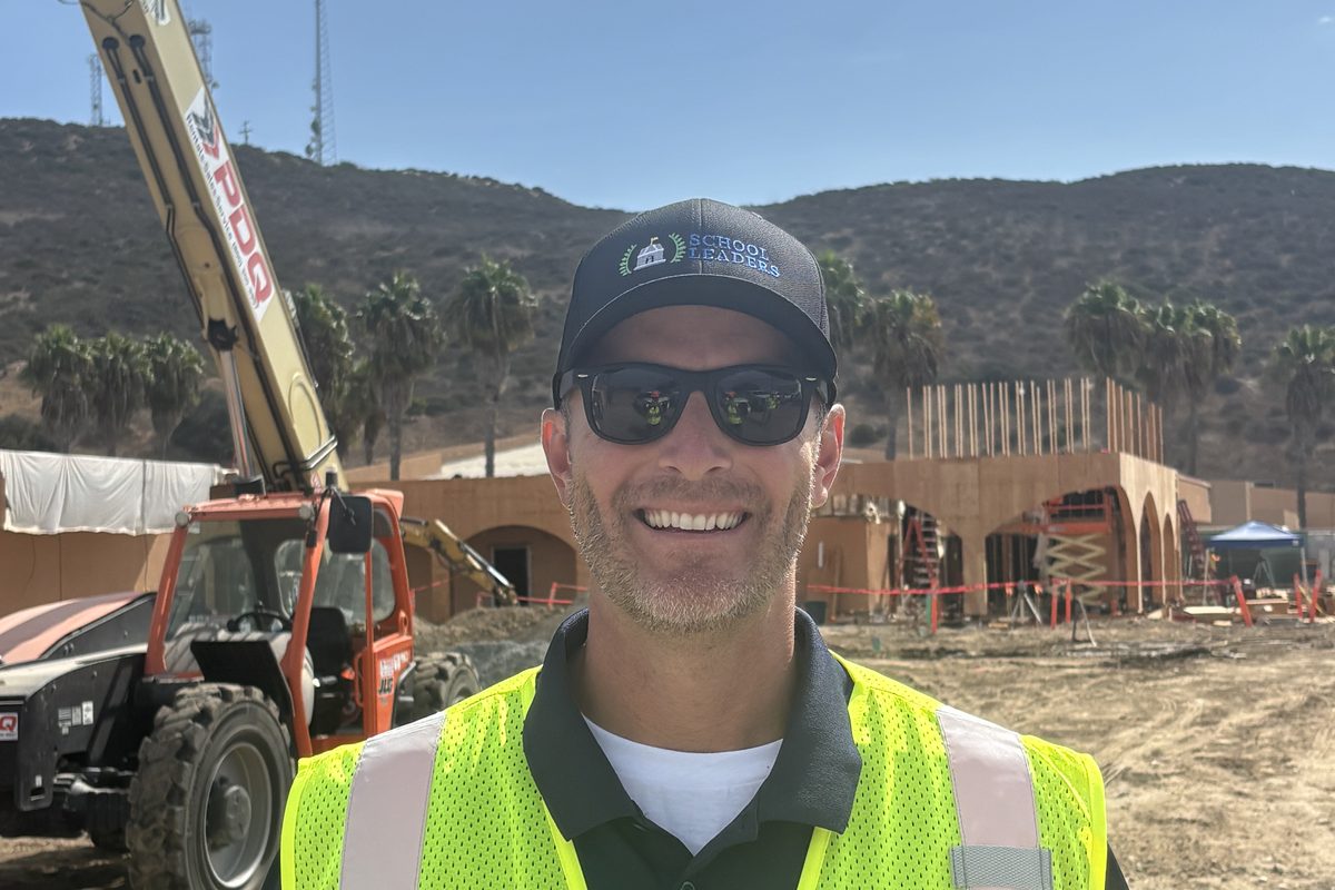 Jay smiling in a safety vest on a school construction site